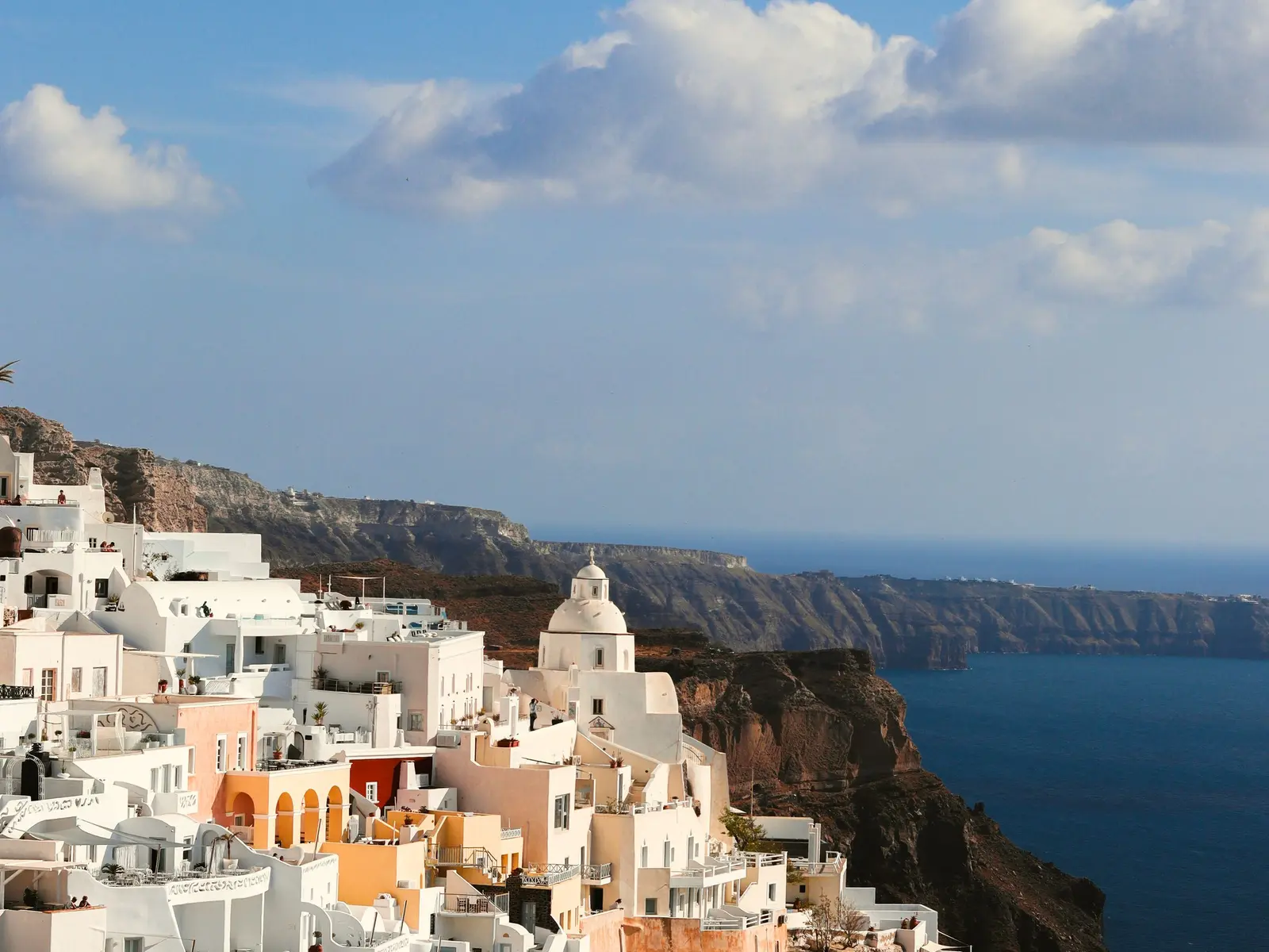 White houses and a chapel on a Greek hillside above the sea